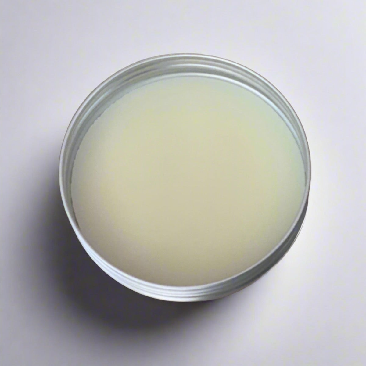 2 oz tin of lemon butter face cream showcasing its light yellow color and creamy texture