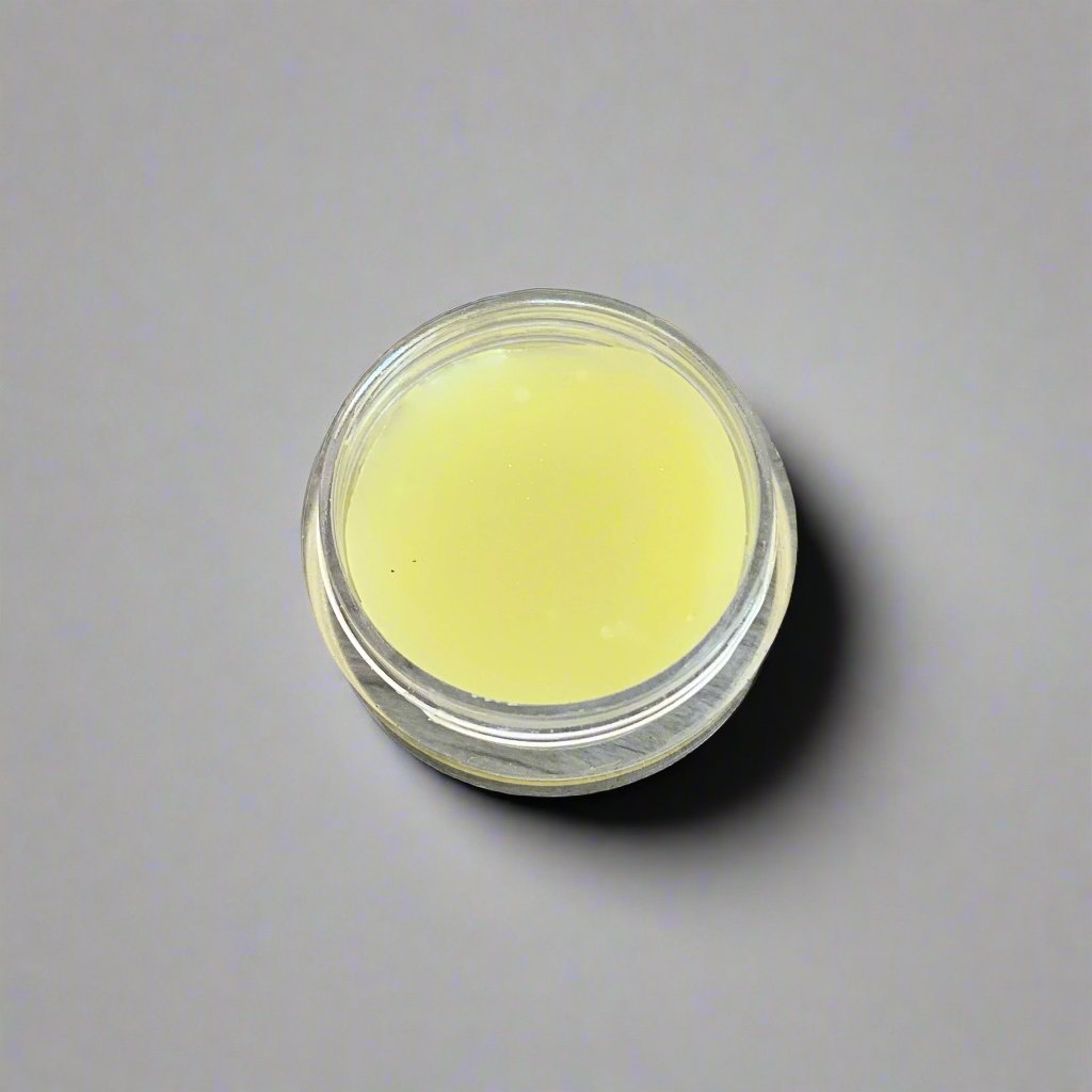 A jar of Coastal Moon Olive Oil Face Cream with a rich, creamy texture visible. The jar is set against a neutral background, highlighting its elegant design.