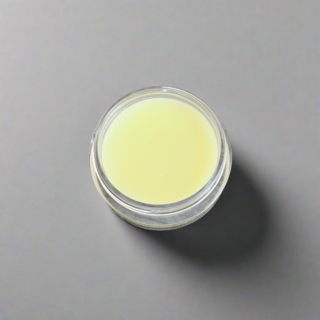 A jar of Tropical Reef Argan Face Cream with a creamy texture visible. The jar is clear and is set against a neutral background, emphasizing its elegant design.