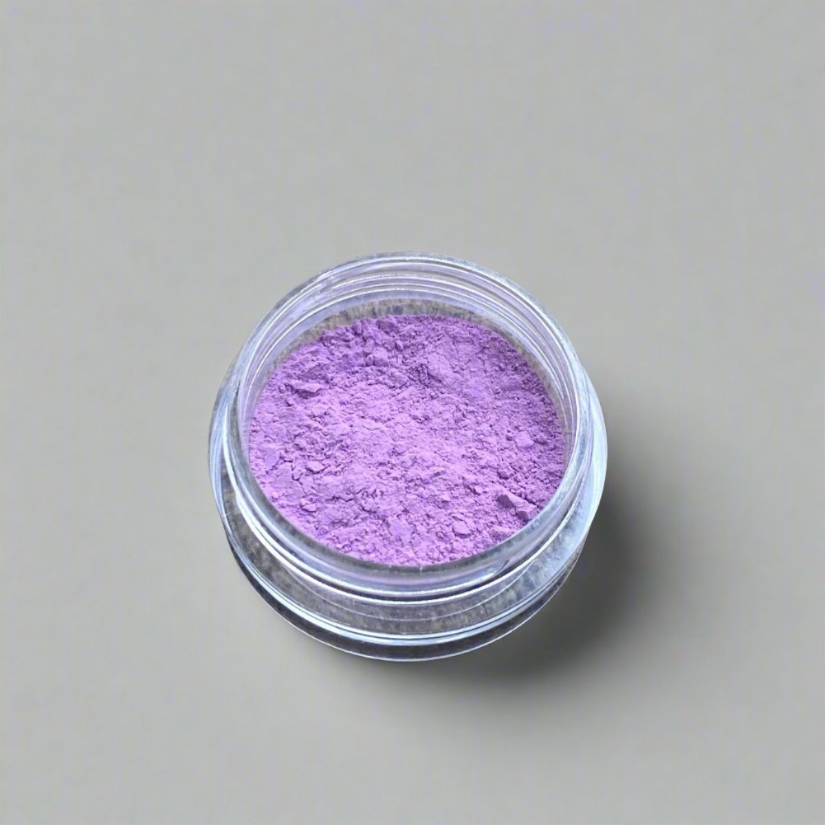 A small cosmetic jar of azalea pink loose powder blush displaying its color and texture.