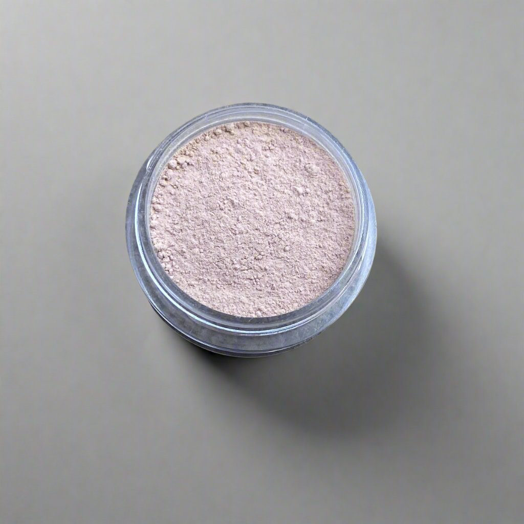 A mini jar of ivory loose powder foundation, showing its color and texture.