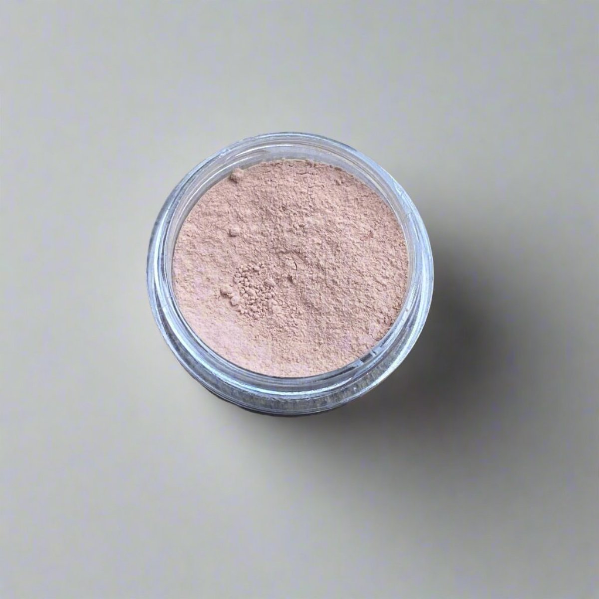 A mini jar of ivory beige loose powder foundation, showing its color and texture.