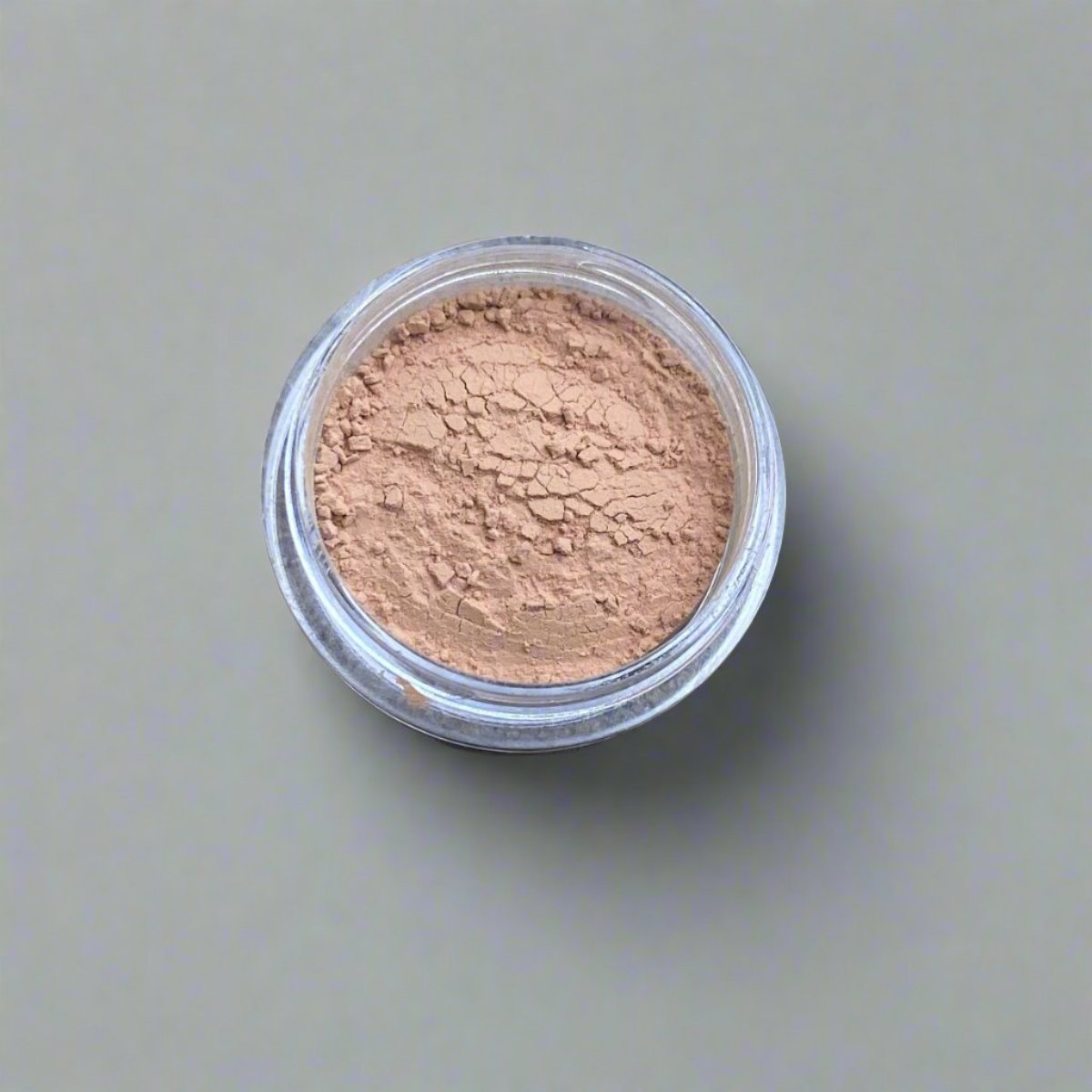 A mini jar of medium beige loose powder foundation, showing its color and texture.