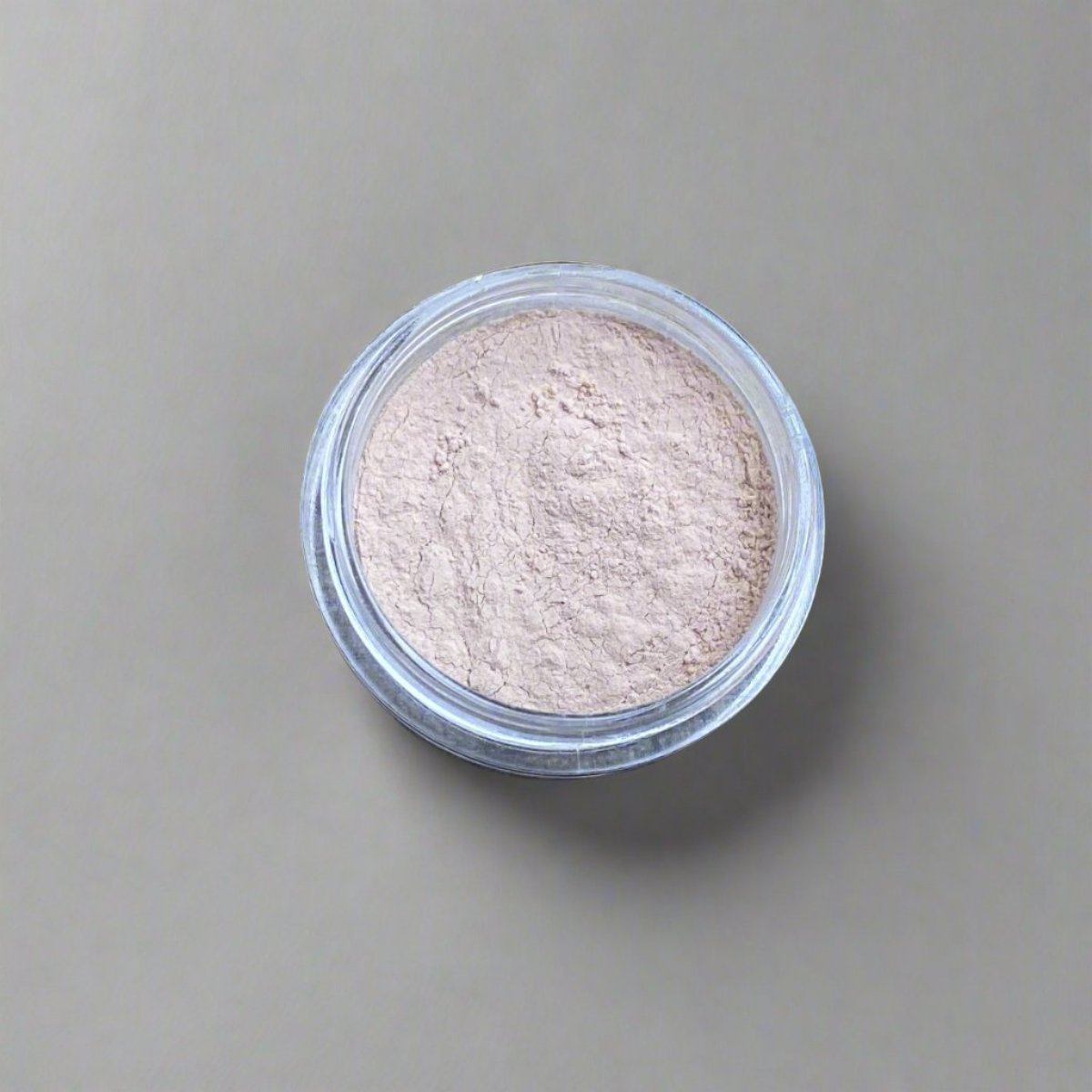 A mini jar of porcelain loose powder foundation, showing its color and texture.