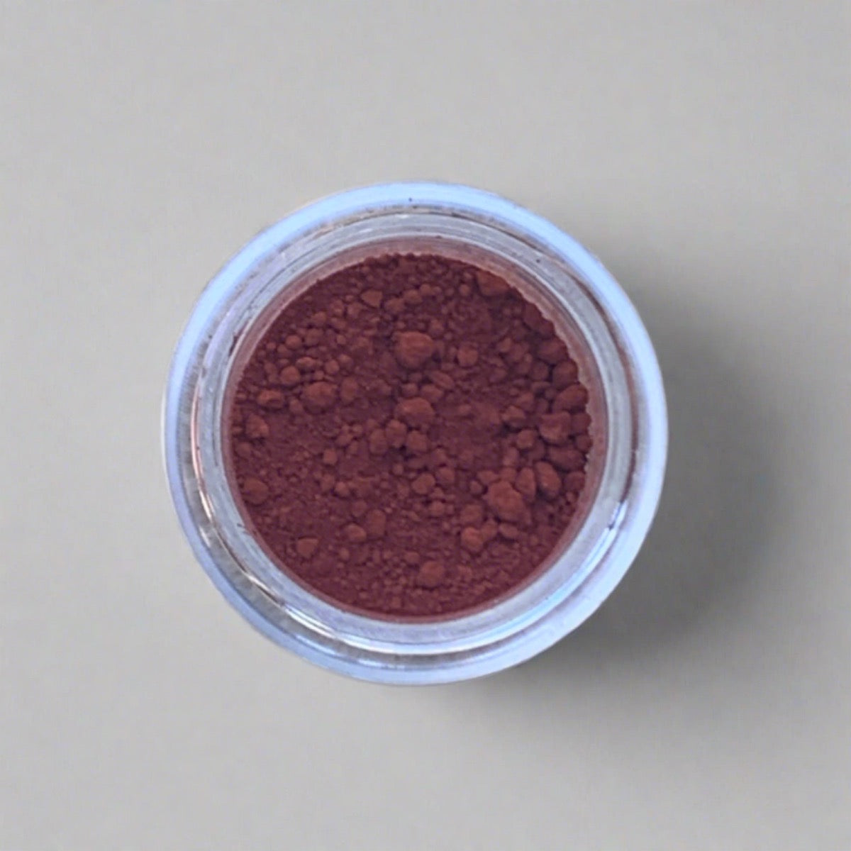 Swatch of reddish brown eyeshadow loose powder, displaying its color