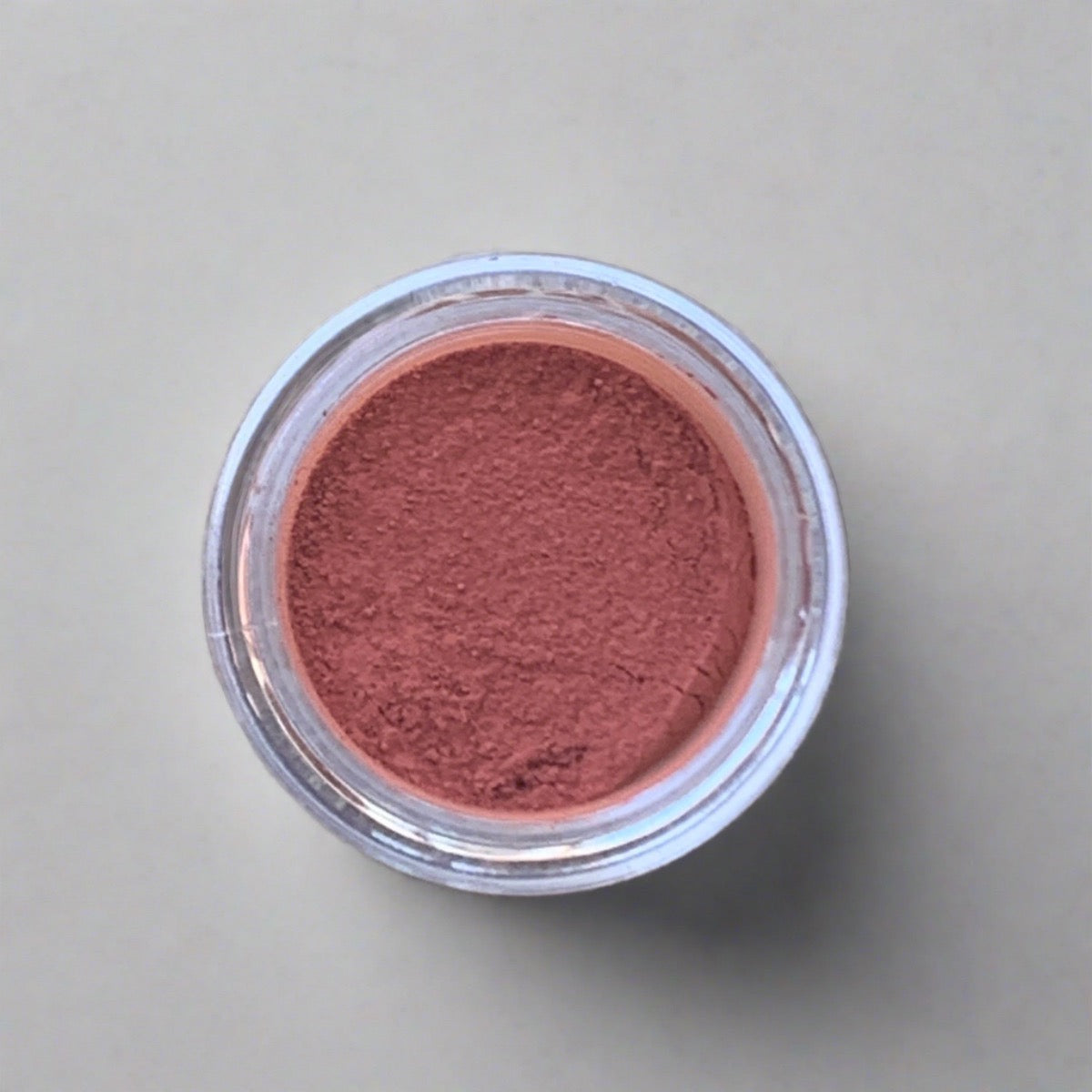 Swatch of pinkish orange eyeshadow loose powder, displaying its color