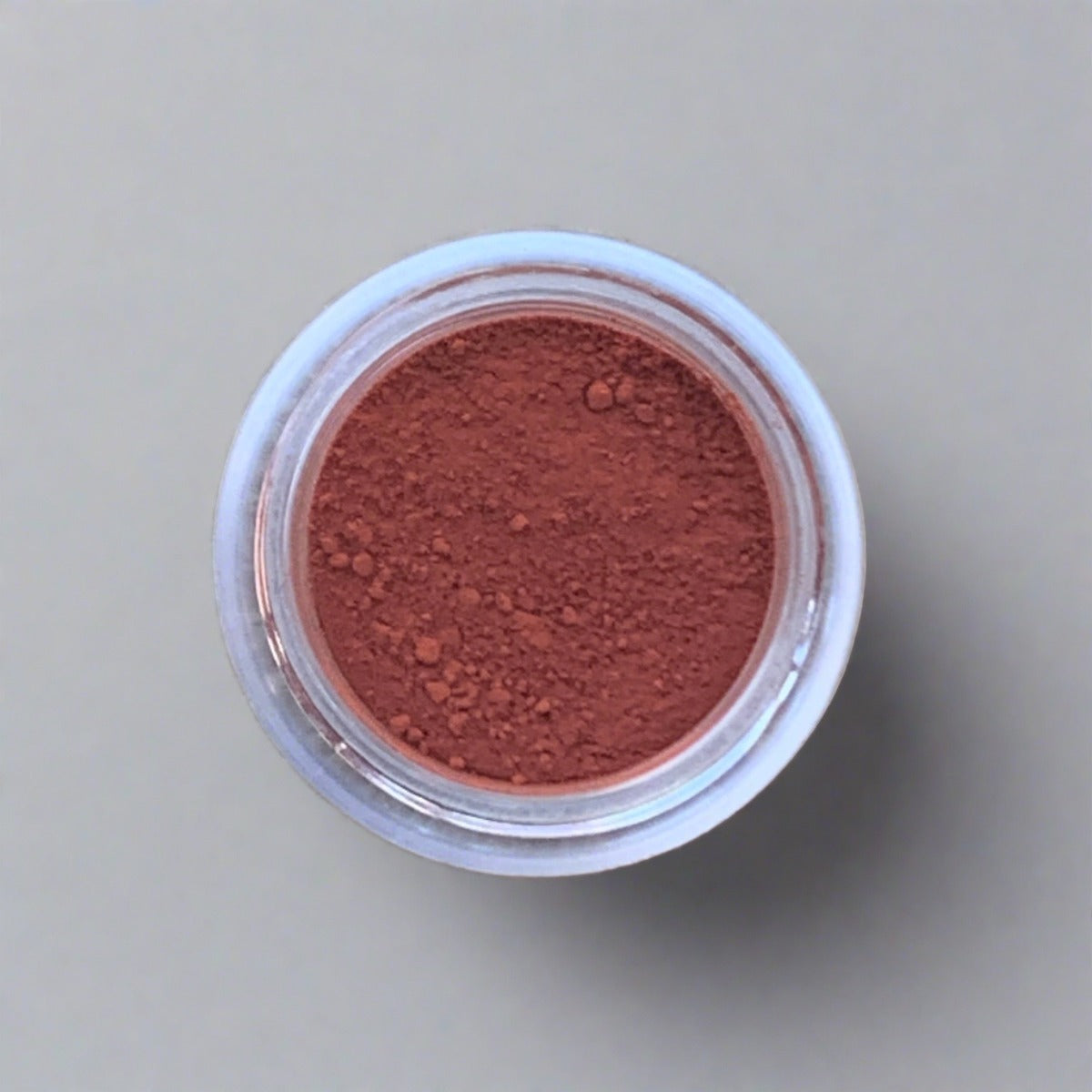 Swatch of reddish orange eyeshadow loose powder, displaying its color