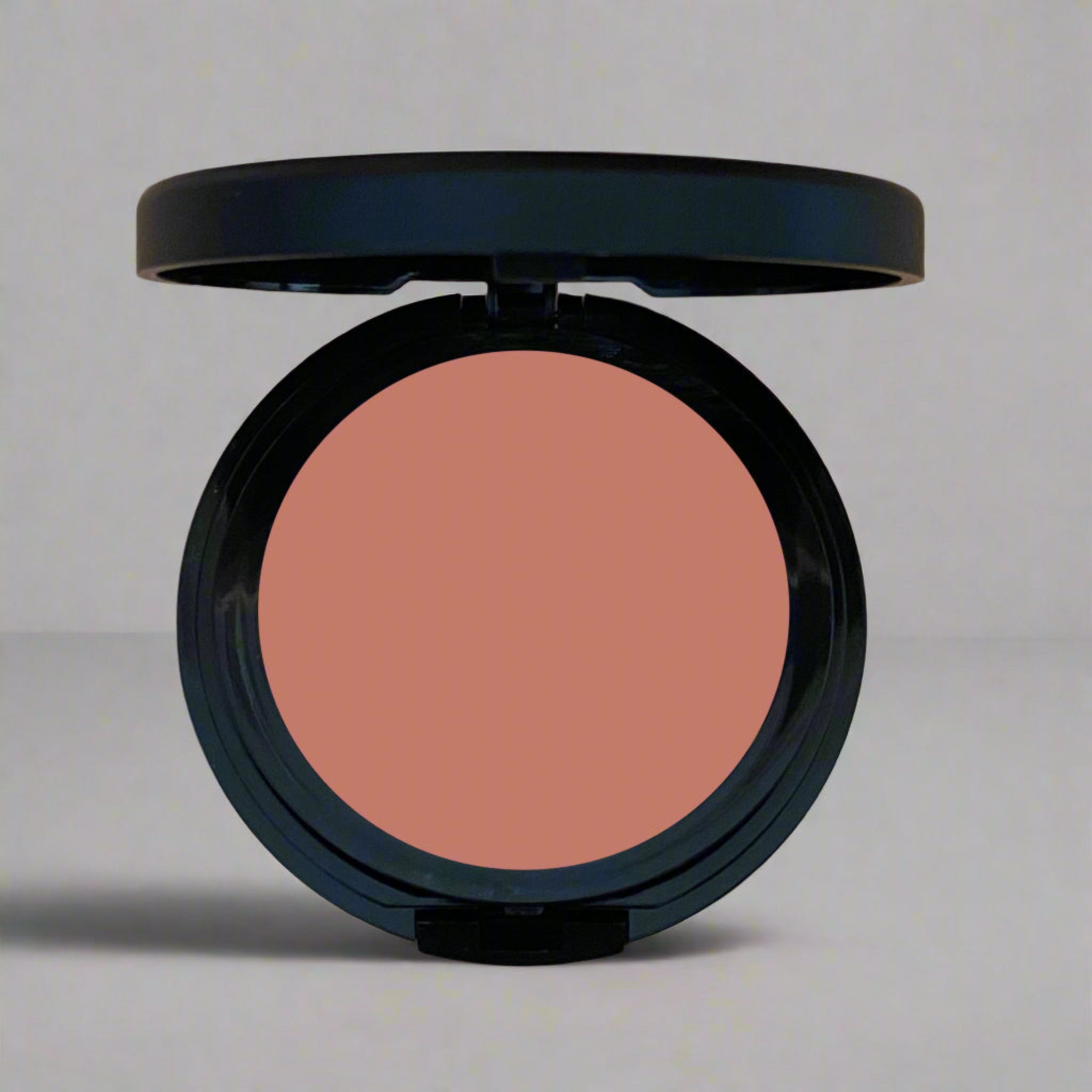 Close-up of a warm clay pressed blush in a sleek compact, part of Coastal Classic Creations' mindful beauty collection. Designed to enhance natural beauty with a soft, radiant finish.