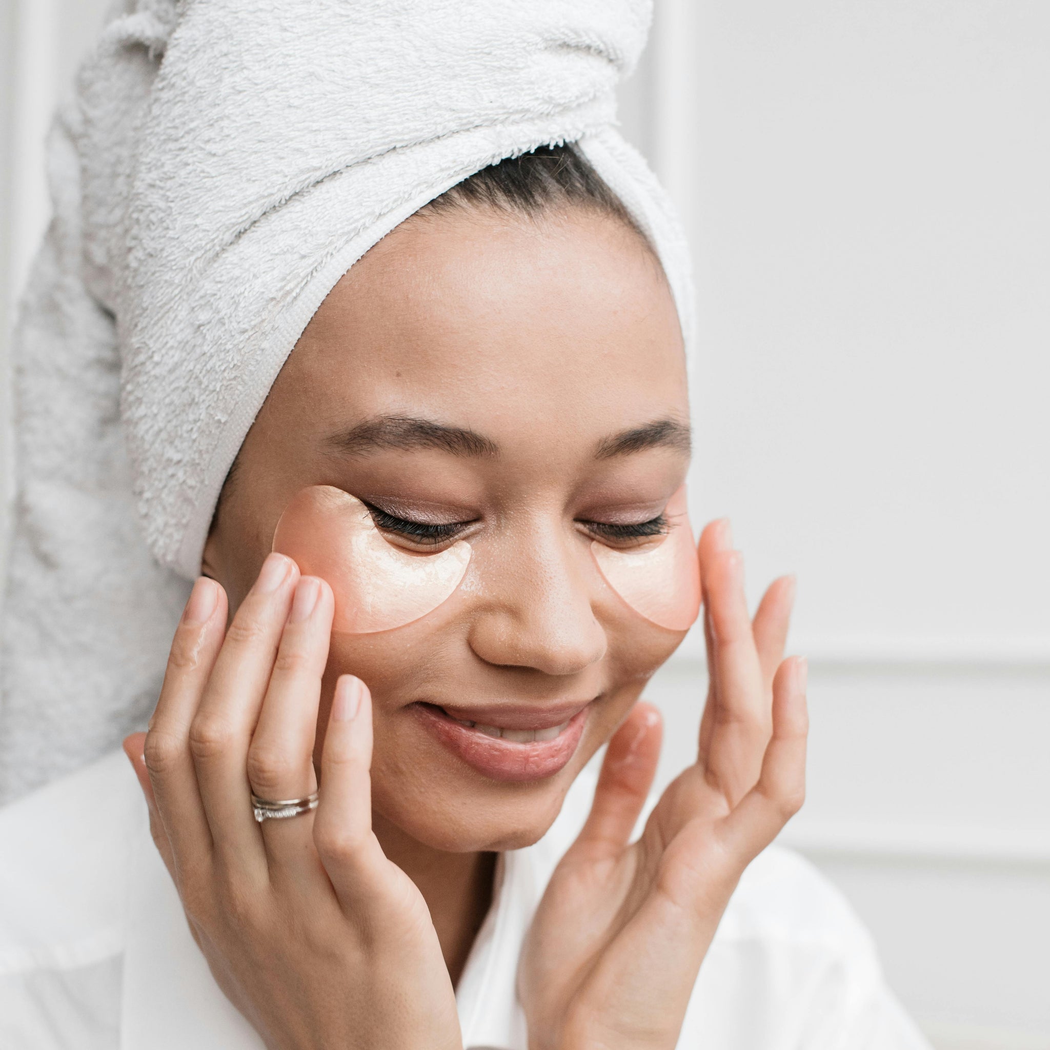 A Woman in a Head Towel using Under Eye Masks representing Coastal Classic Creations Taking Care Of Me Campaign Philosophy